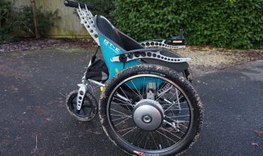 A side view of the Trekinetic GTE powerchair, in teal.